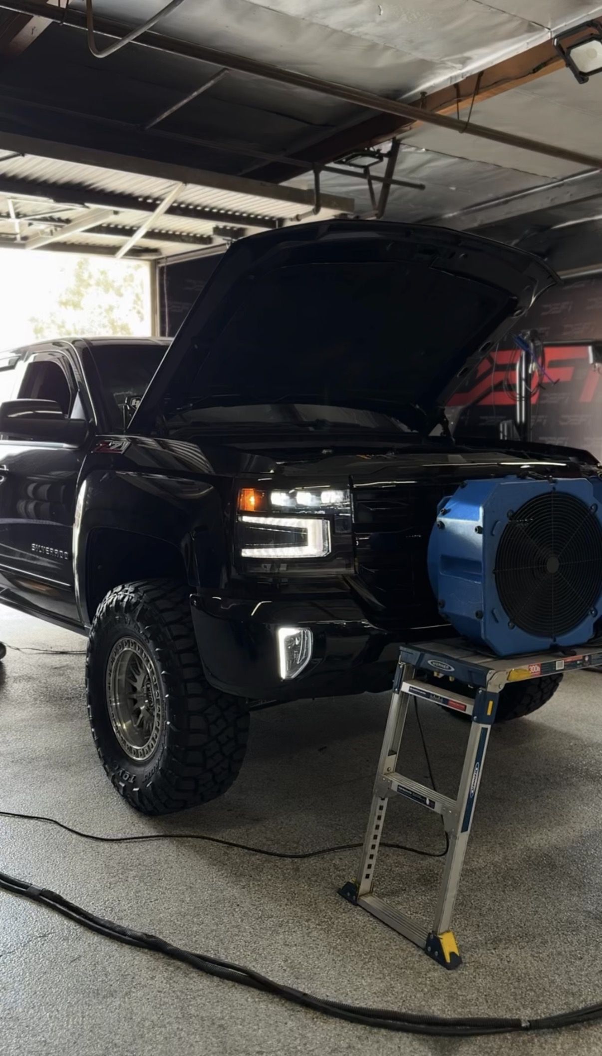 Black Chevrolet Silverado Z71 with the hood up and a cooling fan running during a tuning session at DEFI Motorsports