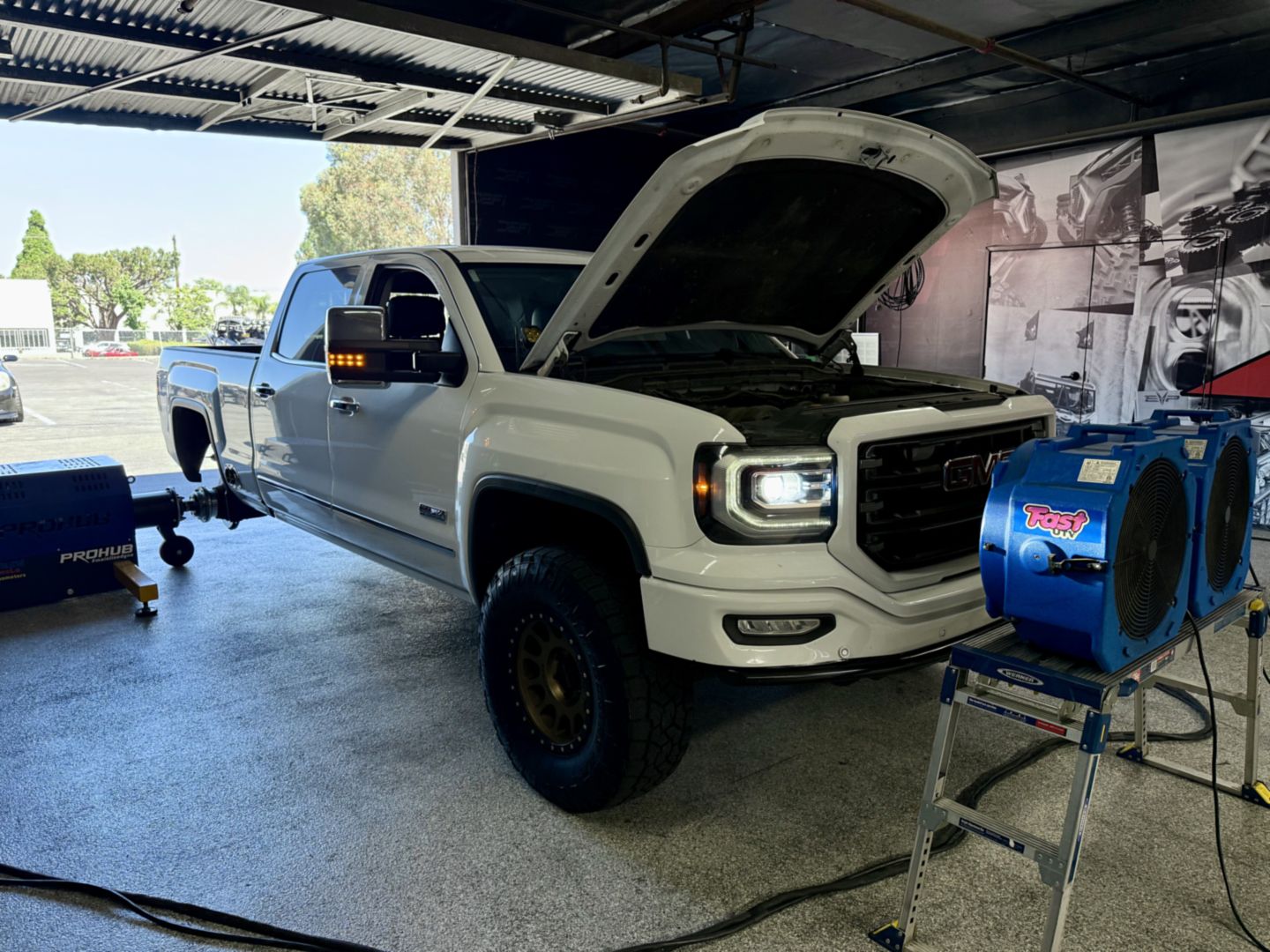 GMC Sierra All Terrain with the hood up beside the Mainline ProHub at DEFI Motorsports