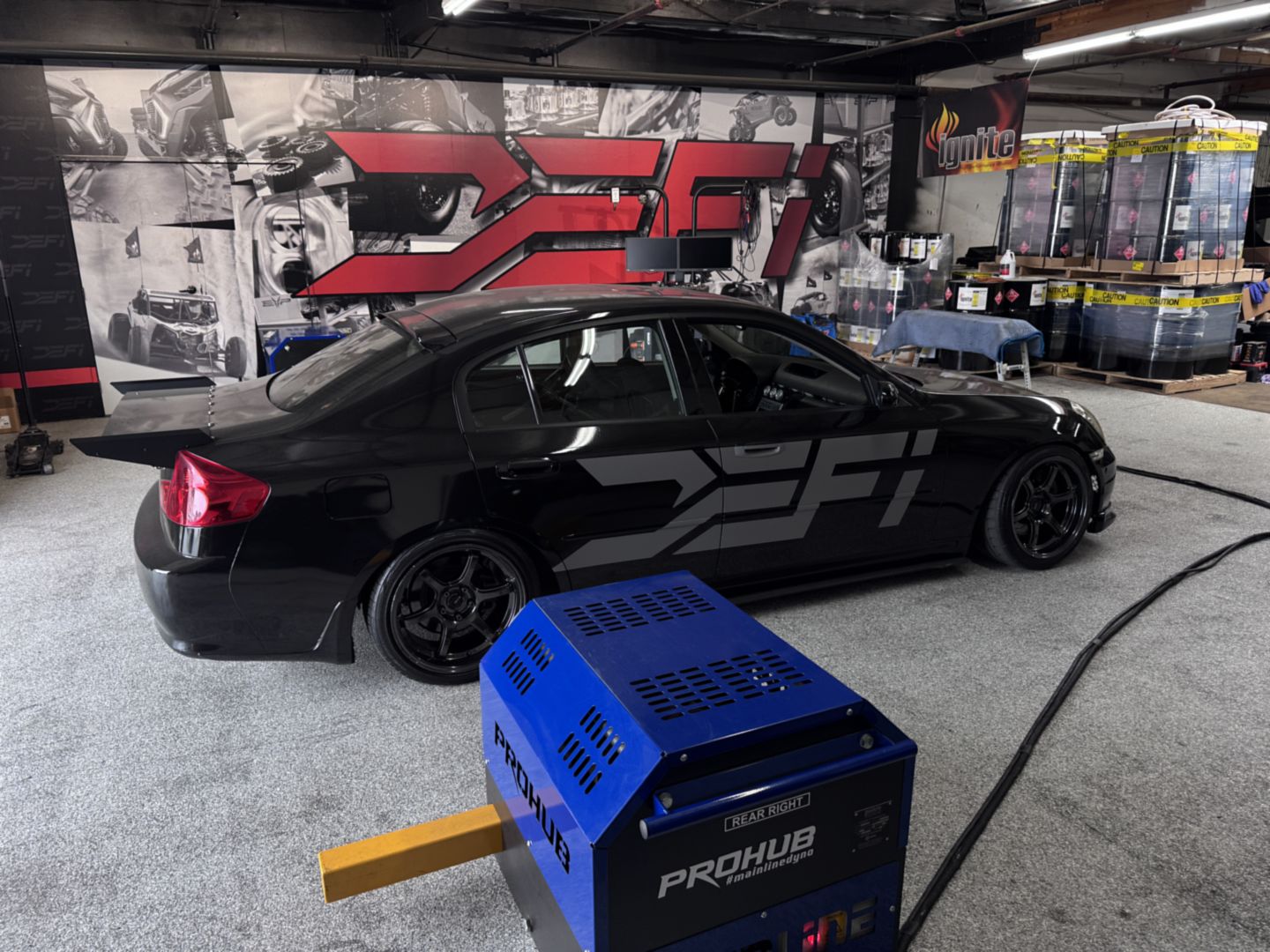 The DEFI Motorsports liveried Infiniti G35 alongside the Mainline ProHub dyno in the Corona workshop