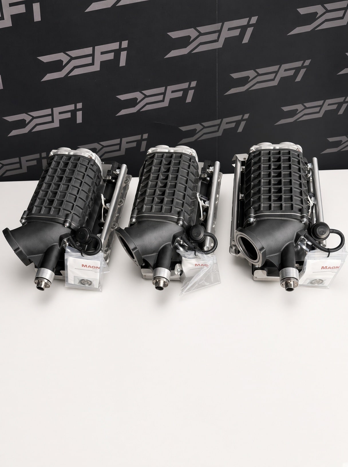 Three Magnuson TVS2300 Hot Rod supercharger kits for LS3 in front of the DEFI Motorsports wall in Corona, California